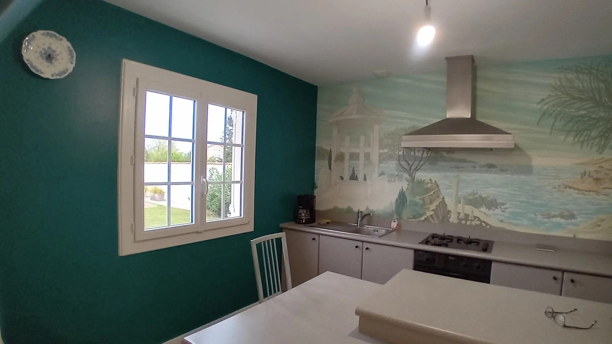 Cuisine avec fresque murale représentant un paysage marin, réalisée par Sylvie Décoration Bergerac/Cours de pile.